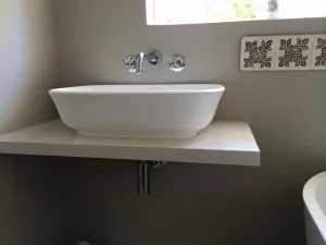 A rectangular counter-top basin on a floating shelf with a wall-mounted mixer.