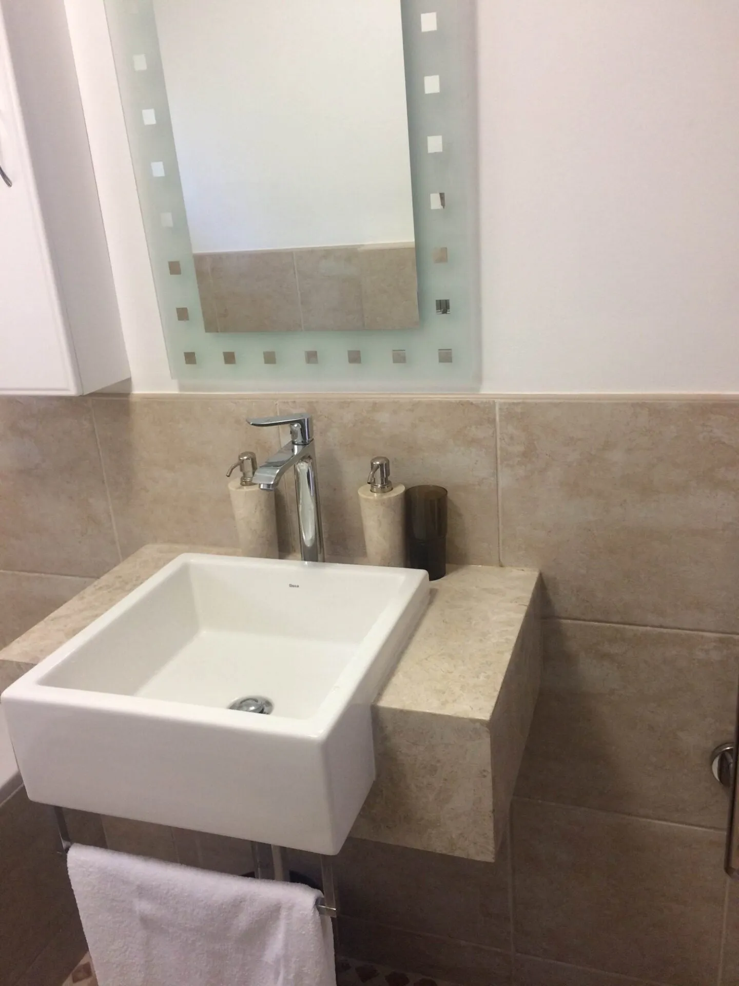 A stone counter-top basin fitted against a tiled wall.