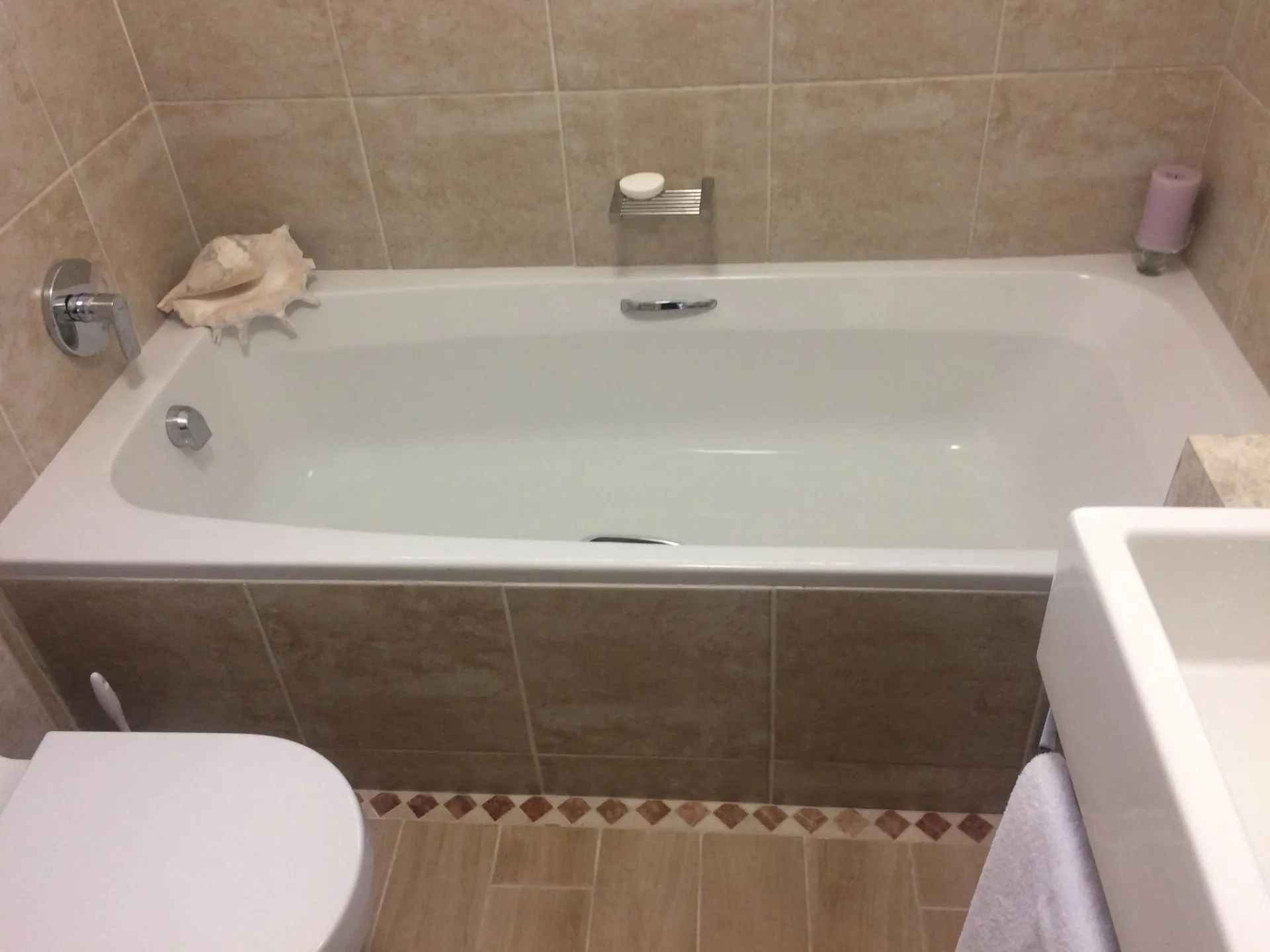A tiled bath surround with a wall-mounted mixer.