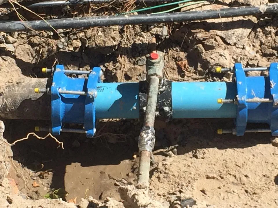 An excavated trench with new blue mains pipe and couplings.