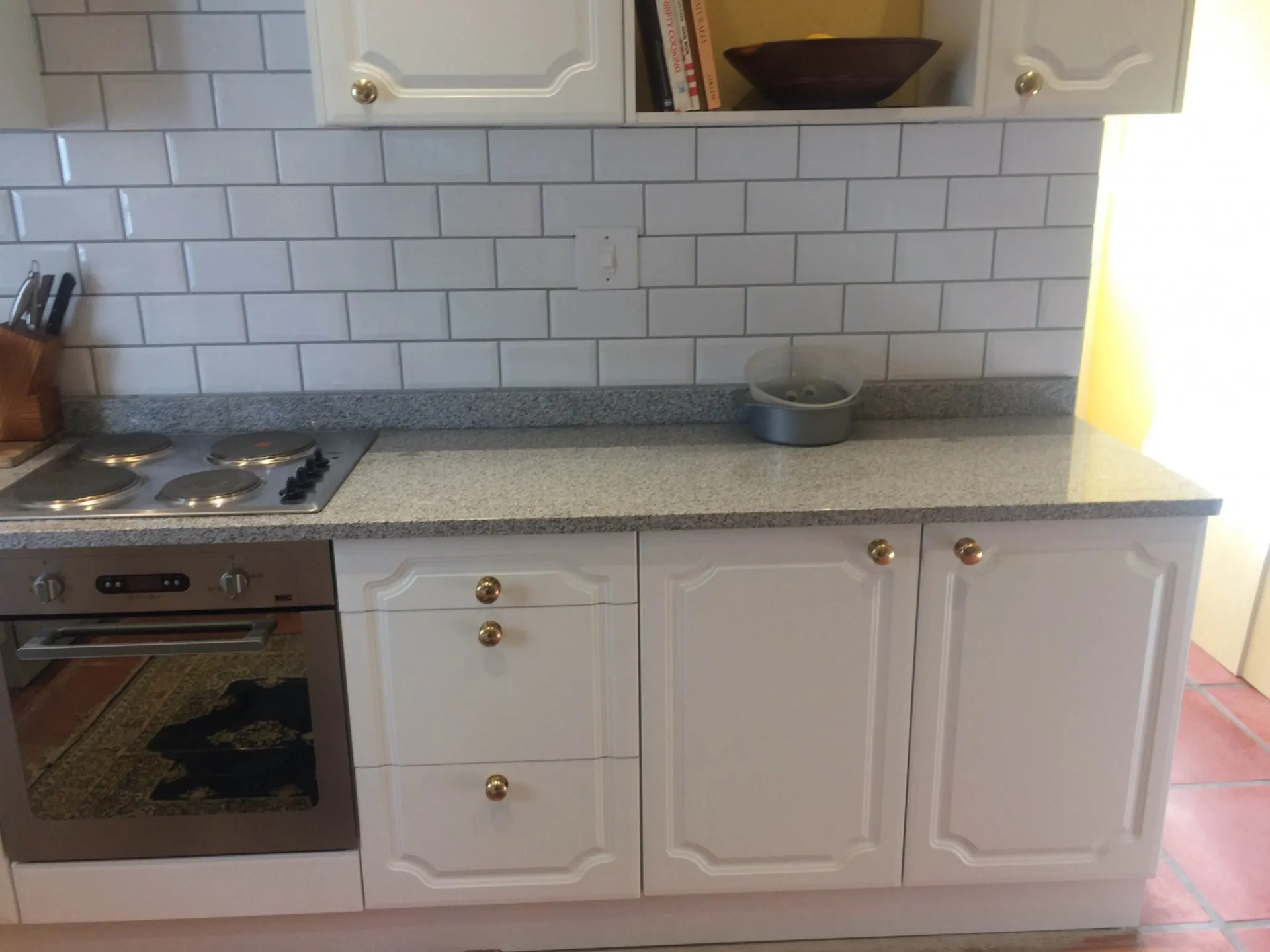 A fitted kitchen with a stainless steel sink and metro-tiled splashback.