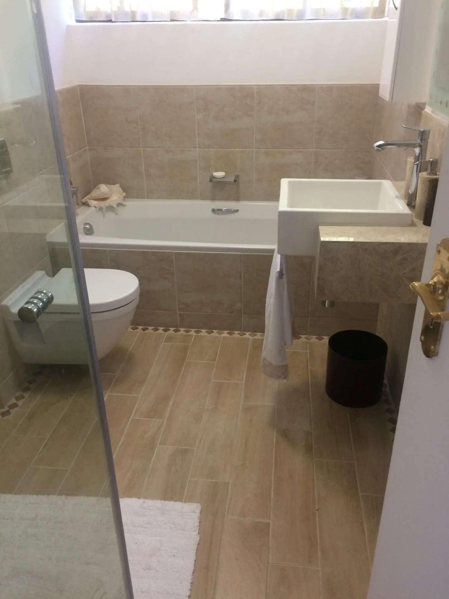 A walk-in shower with a pebble floor and a wall-hung toilet alongside.