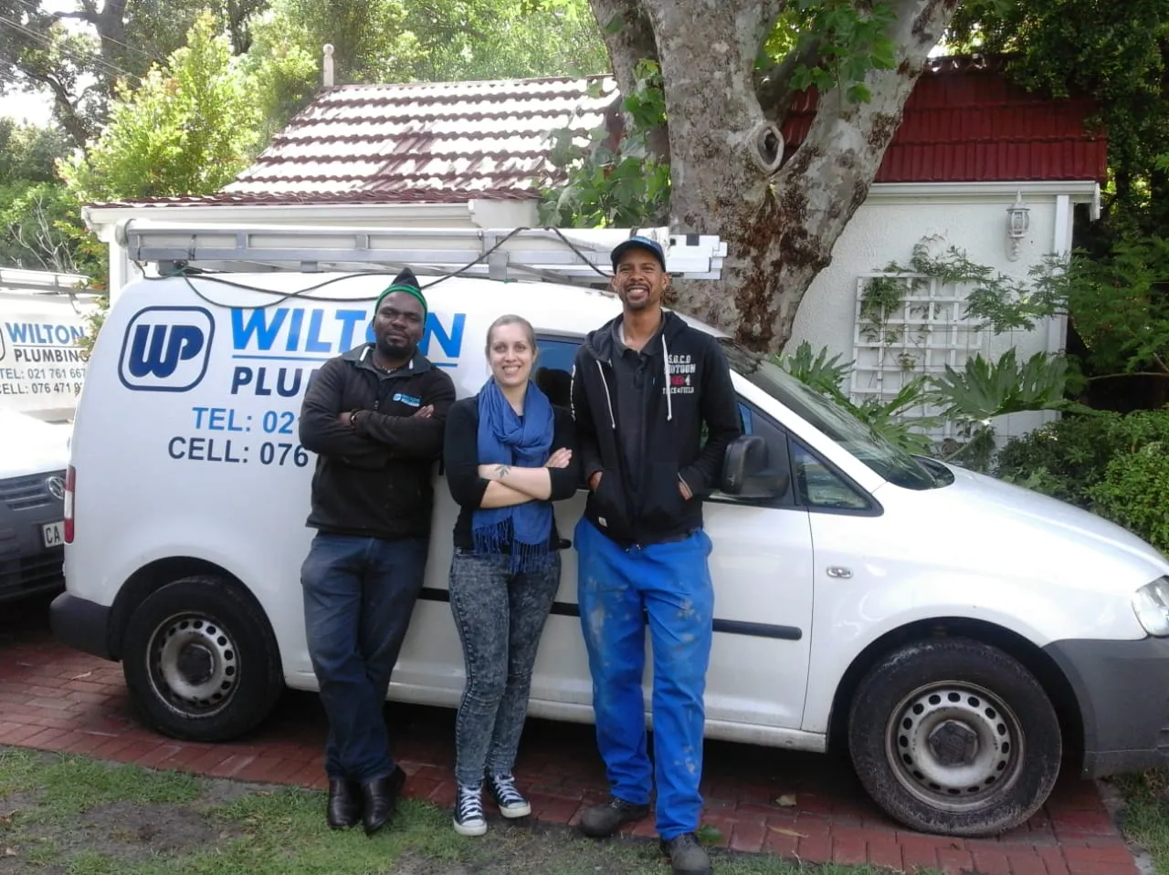 Two Wilton Plumbing team members standing beside a company van.