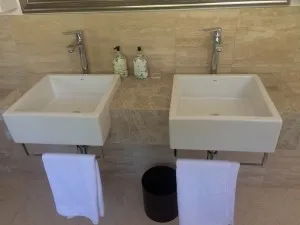 Twin counter-top basins with wall-mounted mixers in a finished bathroom.