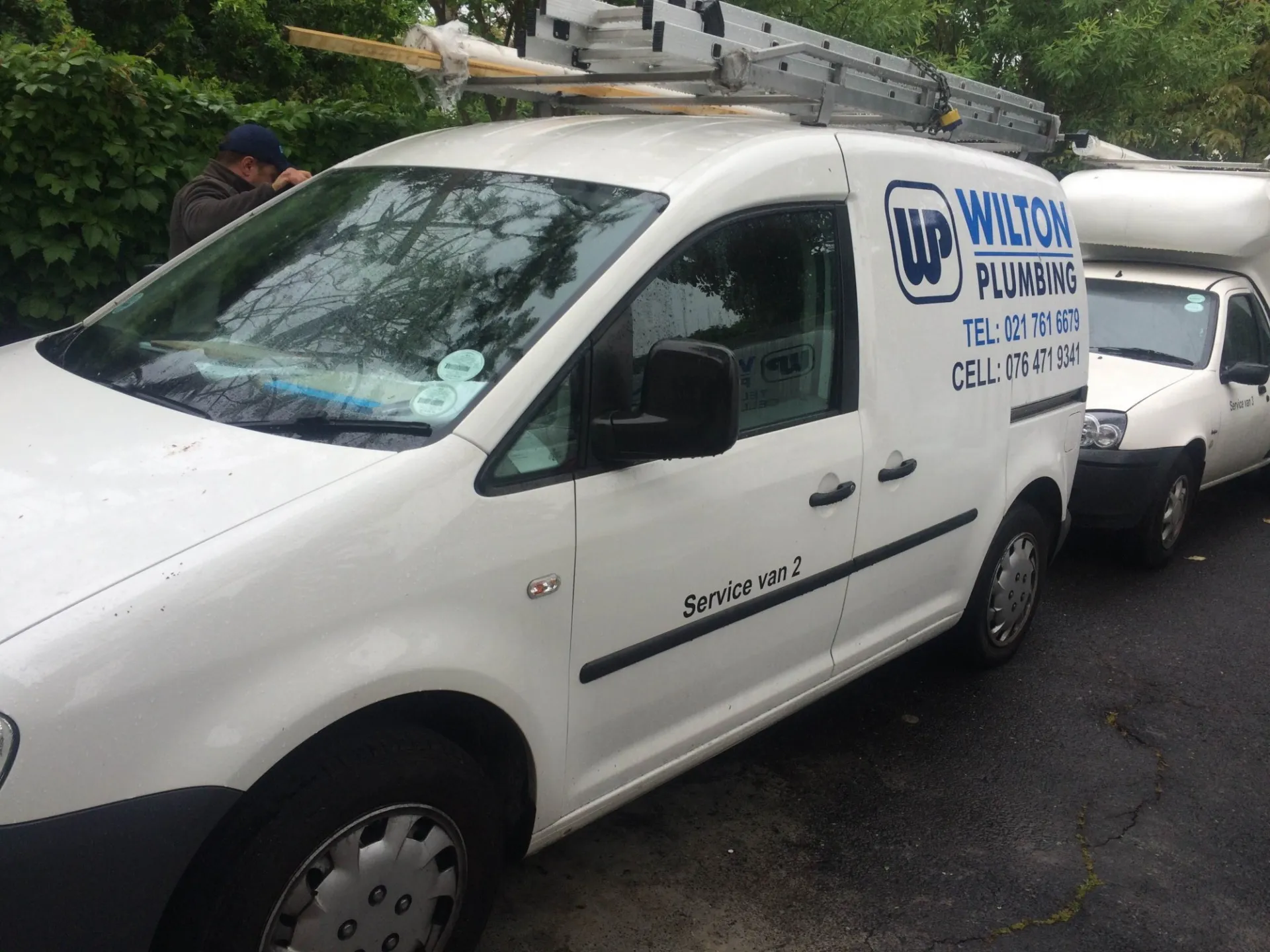 A white Wilton Plumbing panel van parked at a property.